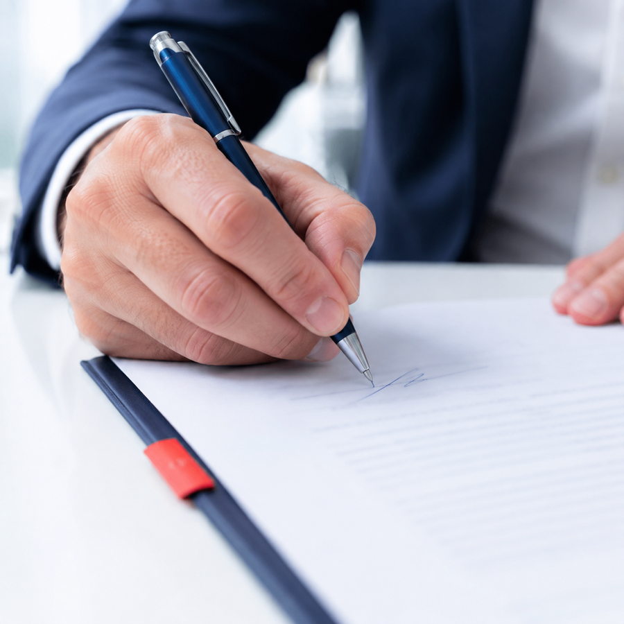 Main signant un document officiel au stylo plume bleu encre, texte illisible